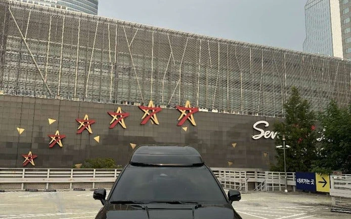 Black car parked in front of Starfield COEX Mall in Seoul, Korea, part of a private city tour.