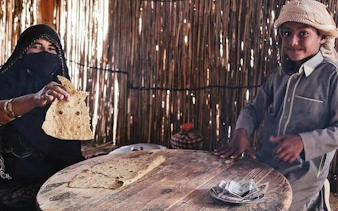 Bedouin woman and child sharing traditional bread in a Sharm El Sheikh desert village.