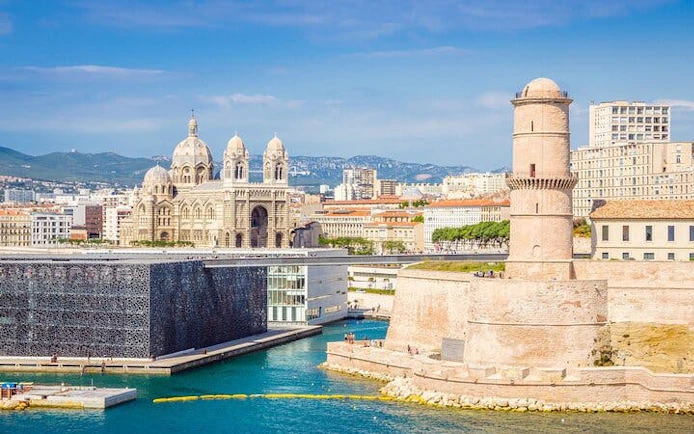 Marseille harbor view with Fort Saint-Jean and Marseille Cathedral in the background.