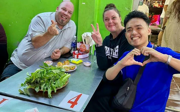 Tourists enjoying street food at a local eatery during a motorbike tour in Ho Chi Minh City.