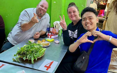 Tourists enjoying street food at a local eatery during a motorbike tour in Ho Chi Minh City.