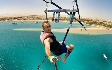 Parasailing over turquoise waters with a view of Hurghada coastline.