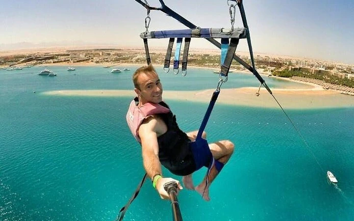 Parasailing over turquoise waters with a view of Hurghada coastline.