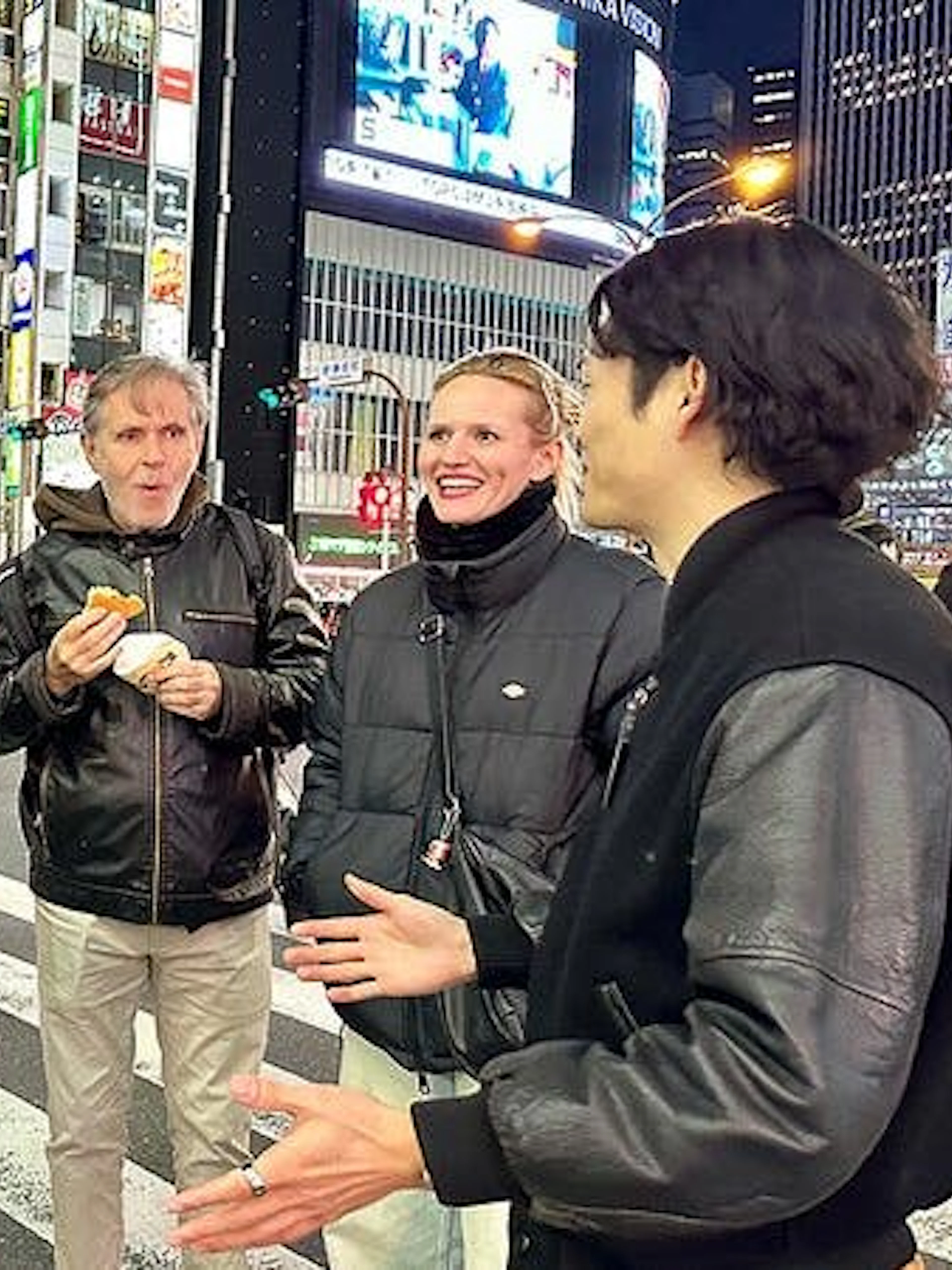 Group enjoying Shibuya walking tour at night, Tokyo, with guide sharing insights.
