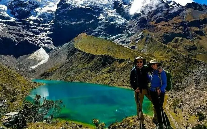 Trekkers at Humantay Lagoon with Andes mountains backdrop, Cusco trek.