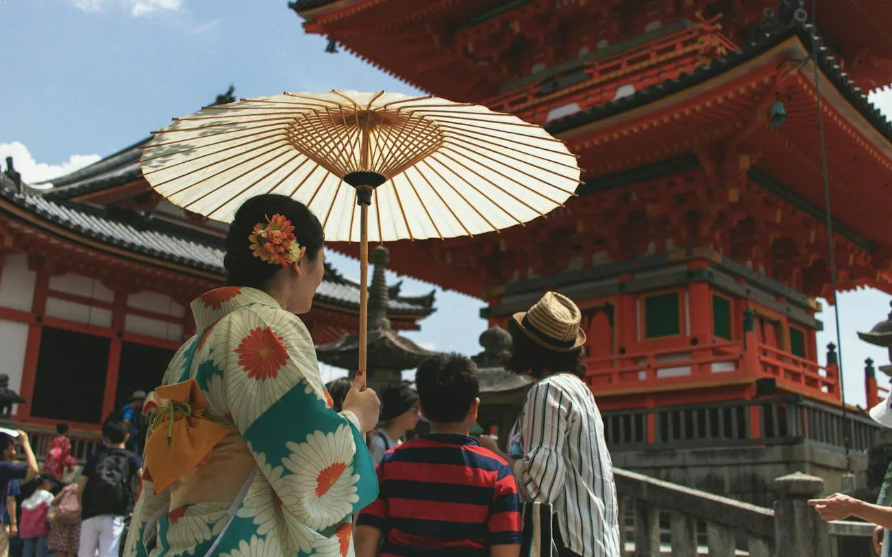 Visitors in traditional attire with parasol at Kiyomizu-dera Temple, Kyoto.