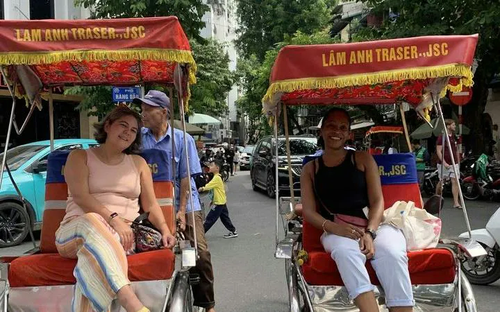 Cyclo tour in Hanoi's Old Quarter with tourists enjoying street view.