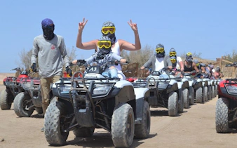 ATV riders on desert safari in Sharm El Sheikh, wearing protective gear and helmets.