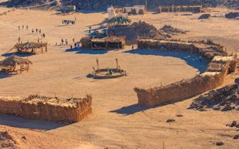 Sharm El Sheikh desert safari with Bedouin village huts and visitors exploring.