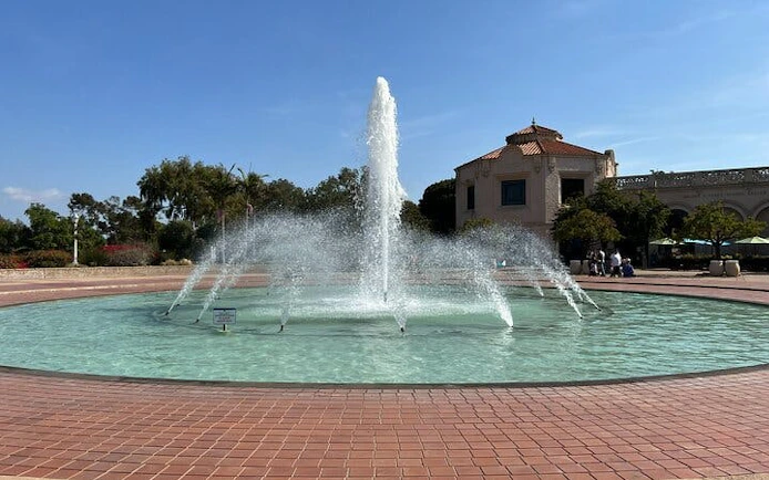 Fountain in Balboa Park, San Diego, with surrounding architecture and trees.