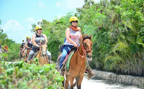Horseback riders on a trail surrounded by lush greenery in Punta Cana.