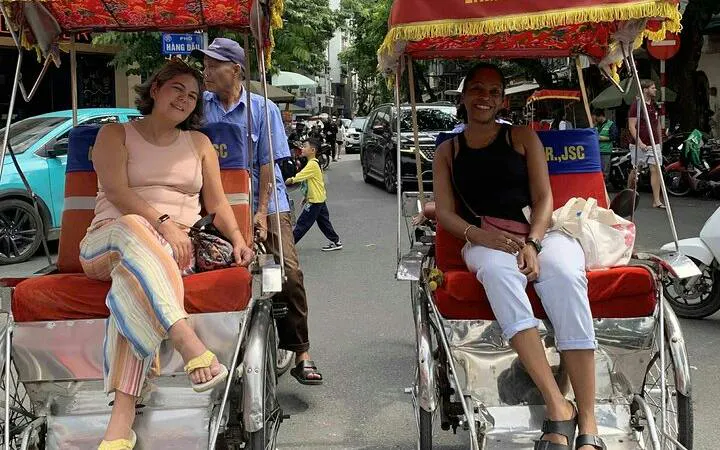 Cyclo tour in Hanoi's Old Quarter with passengers and driver on Train Street.