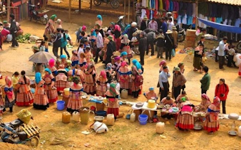 Bac Ha Market with vendors in traditional attire and colorful stalls, Sapa day trip.
