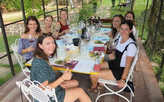 Group enjoying wine tasting and lunch in Tuscany vineyard on Rome to Siena day trip.