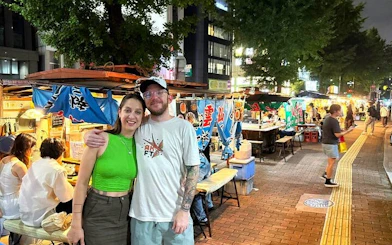 Nakasu food stalls at night with people enjoying guided tour in Fukuoka.