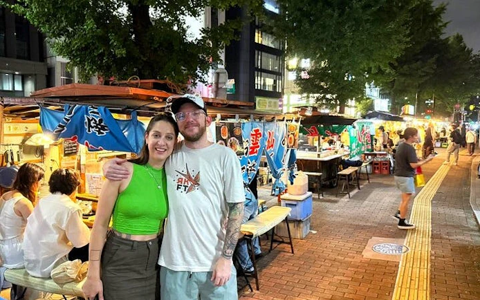 Nakasu food stalls at night with people enjoying guided tour in Fukuoka.