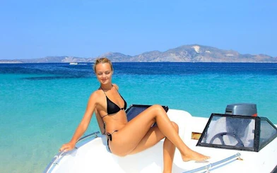 Woman relaxing on a speed boat with clear waters and distant mountains, Hurghada snorkeling trip.