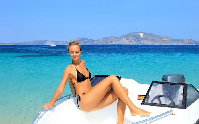Woman relaxing on a speed boat with clear waters and distant mountains, Hurghada snorkeling trip.
