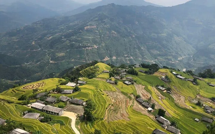 Terraced rice fields and village in Bac Ha, Vietnam, viewed from above during motorbike tour.