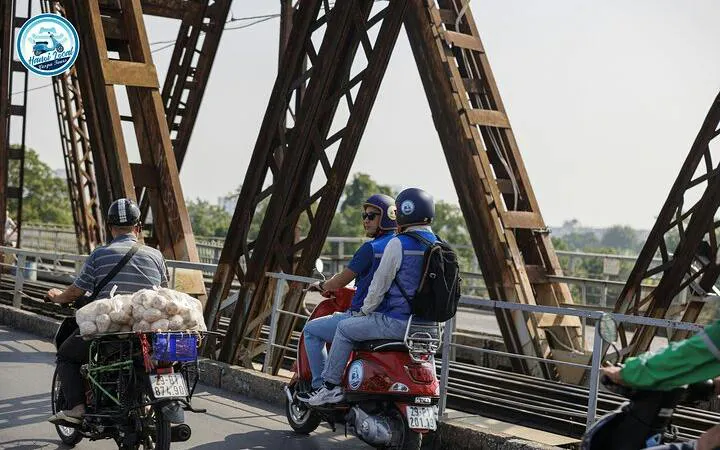 Vespa riders crossing Long Bien Bridge in Hanoi during a half-day tour.