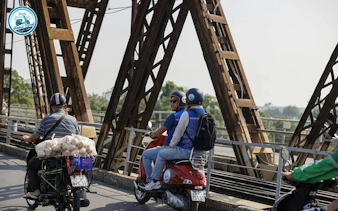 Vespa riders crossing Long Bien Bridge in Hanoi during a half-day tour.