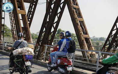 Vespa riders crossing Long Bien Bridge in Hanoi during a half-day tour.