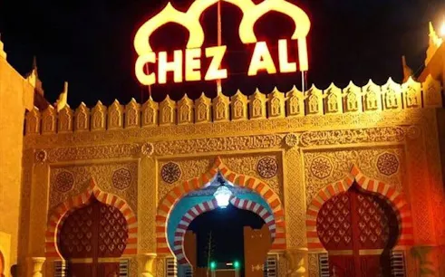 Chez Ali entrance illuminated at night, Marrakesh folklore show venue.