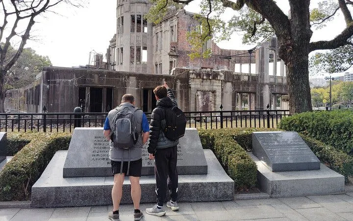 Two visitors observe the Hiroshima Atomic Bomb Dome during a guided tour.