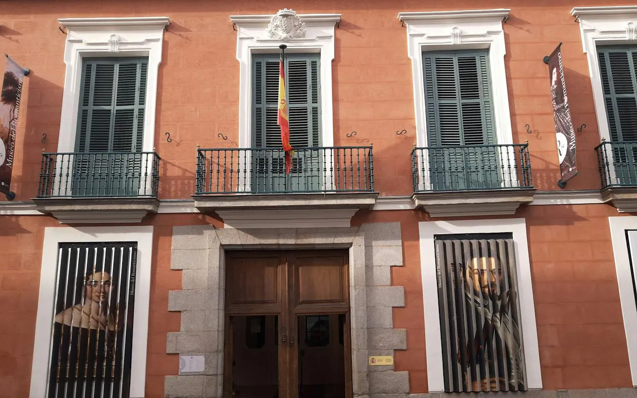 Facade of Museo del Romanticismo in Madrid with Spanish flag and portraits.