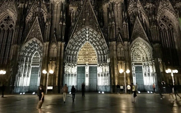 Cologne Cathedral illuminated at night during self-guided haunted city exploration game.