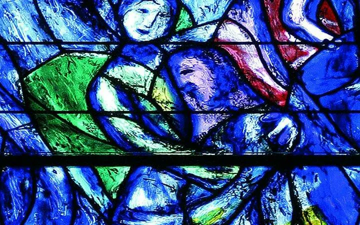 Stained glass artwork in Zurich church, featuring vibrant blue and green hues.
