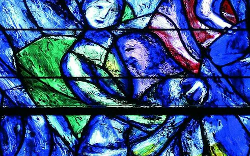 Stained glass artwork in Zurich church, featuring vibrant blue and green hues.