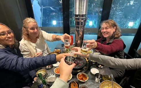 Group enjoying Korean BBQ dinner with drinks in Gangnam, Seoul.