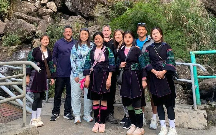Group of tourists with local guides on Sapa Private Car Tour near rocky landscape.