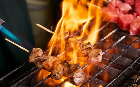 Grilled skewers cooking over open flame at Tsukiji Fish Market tour.