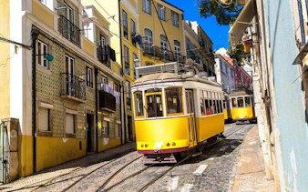 Yellow trams on a cobblestone street in Lisbon's historic district.