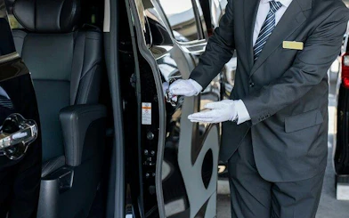 Private chauffeur opening car door for Osaka City to Kansai Airport transfer.