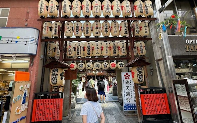 Kyoto Nishiki Market entrance with lanterns and visitors exploring shops.