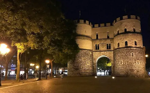 Medieval gate illuminated at night in Cologne during haunted city exploration game.