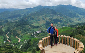 Couple on a wooden platform overlooking terraced rice fields in Mu Cang Chai, Vietnam.