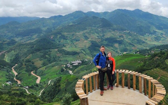 Couple on a wooden platform overlooking terraced rice fields in Mu Cang Chai, Vietnam.