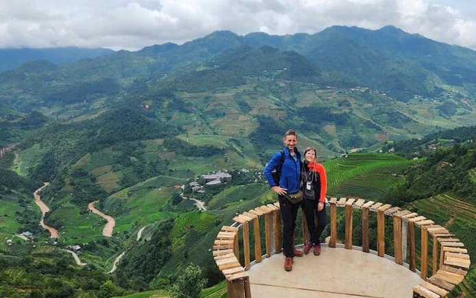 Couple on a wooden platform overlooking terraced rice fields in Mu Cang Chai, Vietnam.