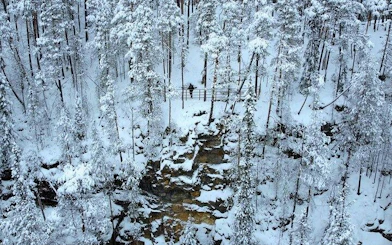 Korouoma Canyon snowy forest with frozen waterfall, Rovaniemi hiking tour.