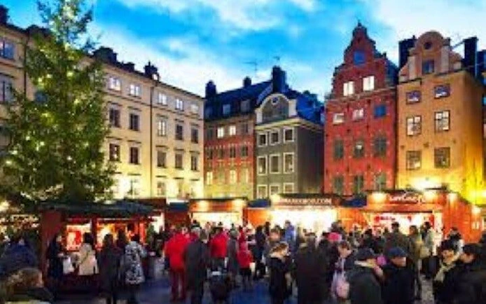 Crowd exploring Gamla Stan's colorful buildings during Stockholm walking tour.