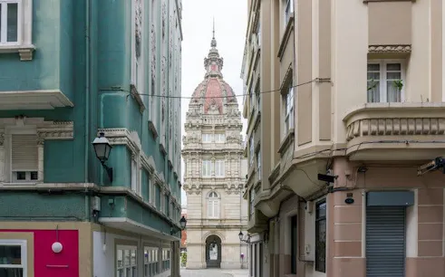 Narrow street view leading to the Palacio Municipal in A Coruña, Spain.