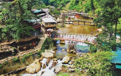 Sapa village with bridges over a river, surrounded by lush greenery and waterfalls.
