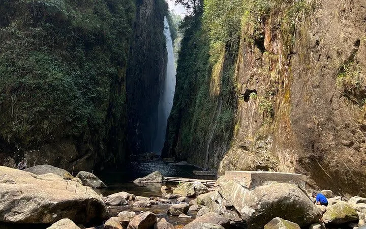 Waterfall cascading between cliffs on Sapa motorbike tour route to Dragon Waterfall and Hidden Village.