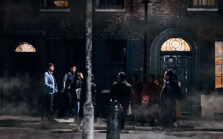 Group on Jack the Ripper walking tour in London, exploring historic crime scene at night.
