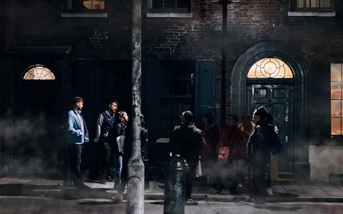 Group on Jack the Ripper walking tour in London, exploring historic crime scene at night.