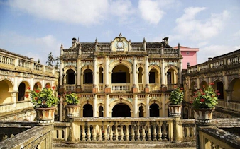 Historic building at Bac Ha Market, Sapa, with ornate arches and potted plants.